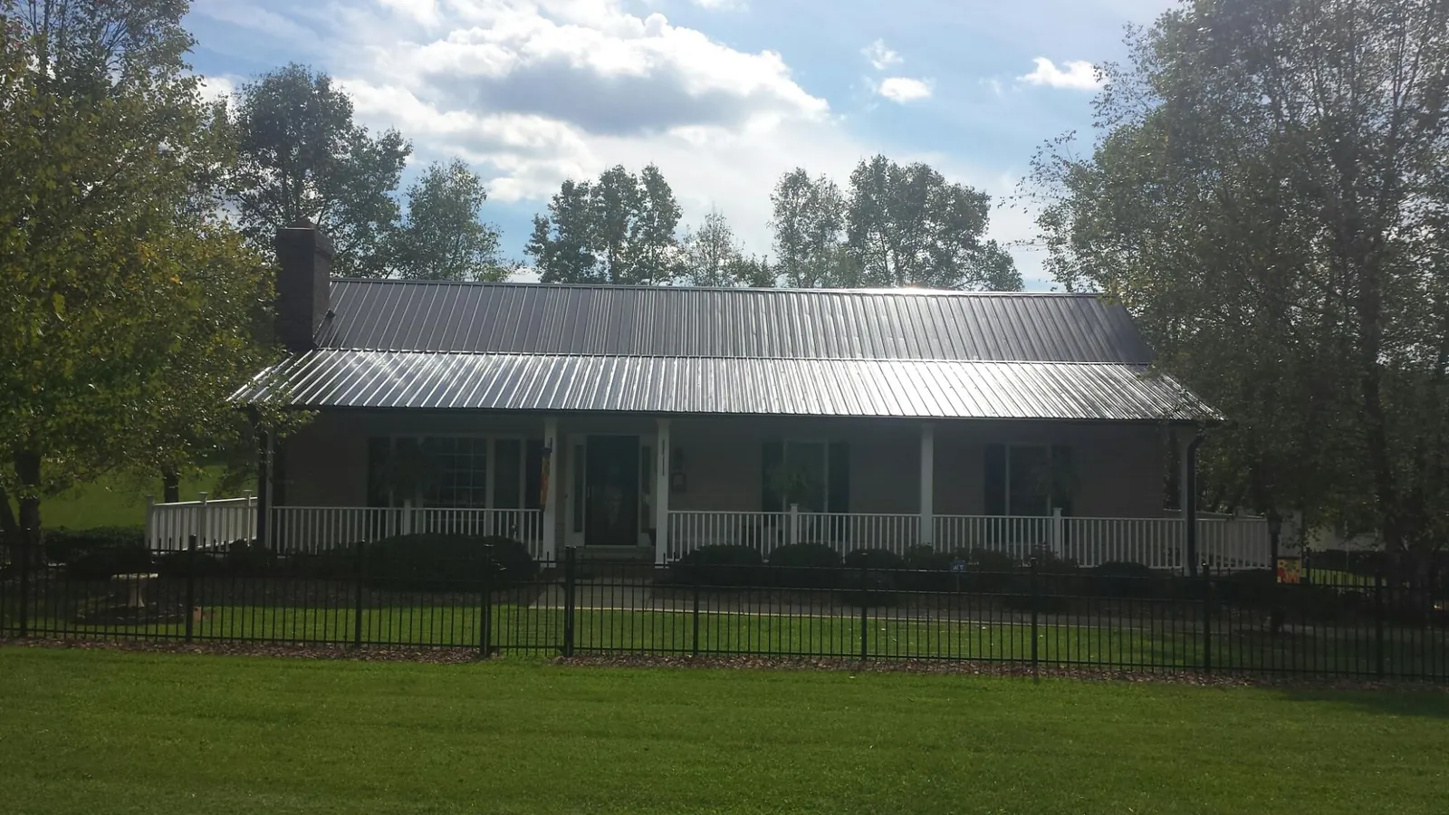 Gray metal roof on a brick ranch with a full width front porch — Gutter Guard Installation work by our crew in Kinards