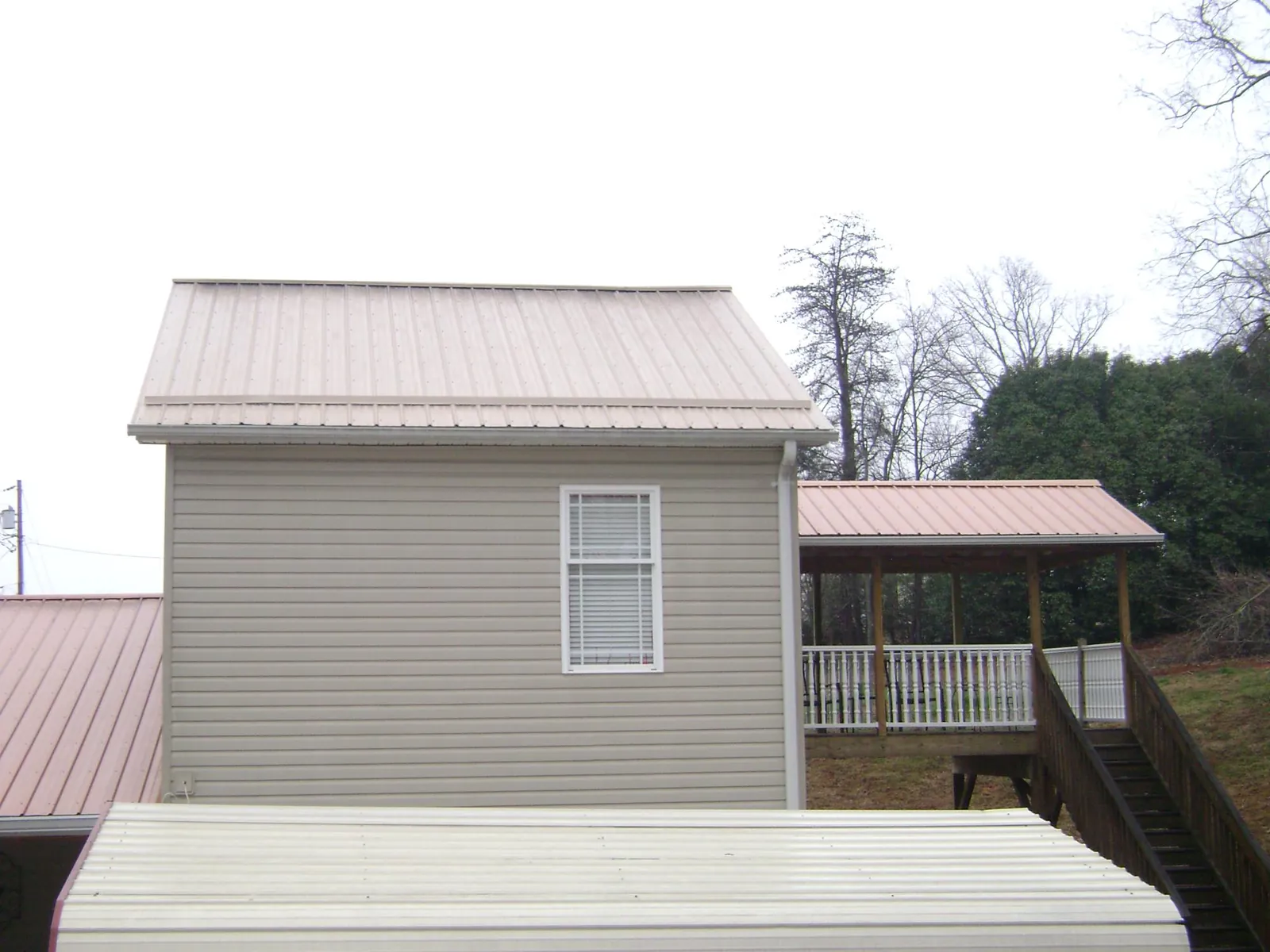 Tan metal roofs on a two story addition and attached porch, from a Roof Replacement job in Kinards